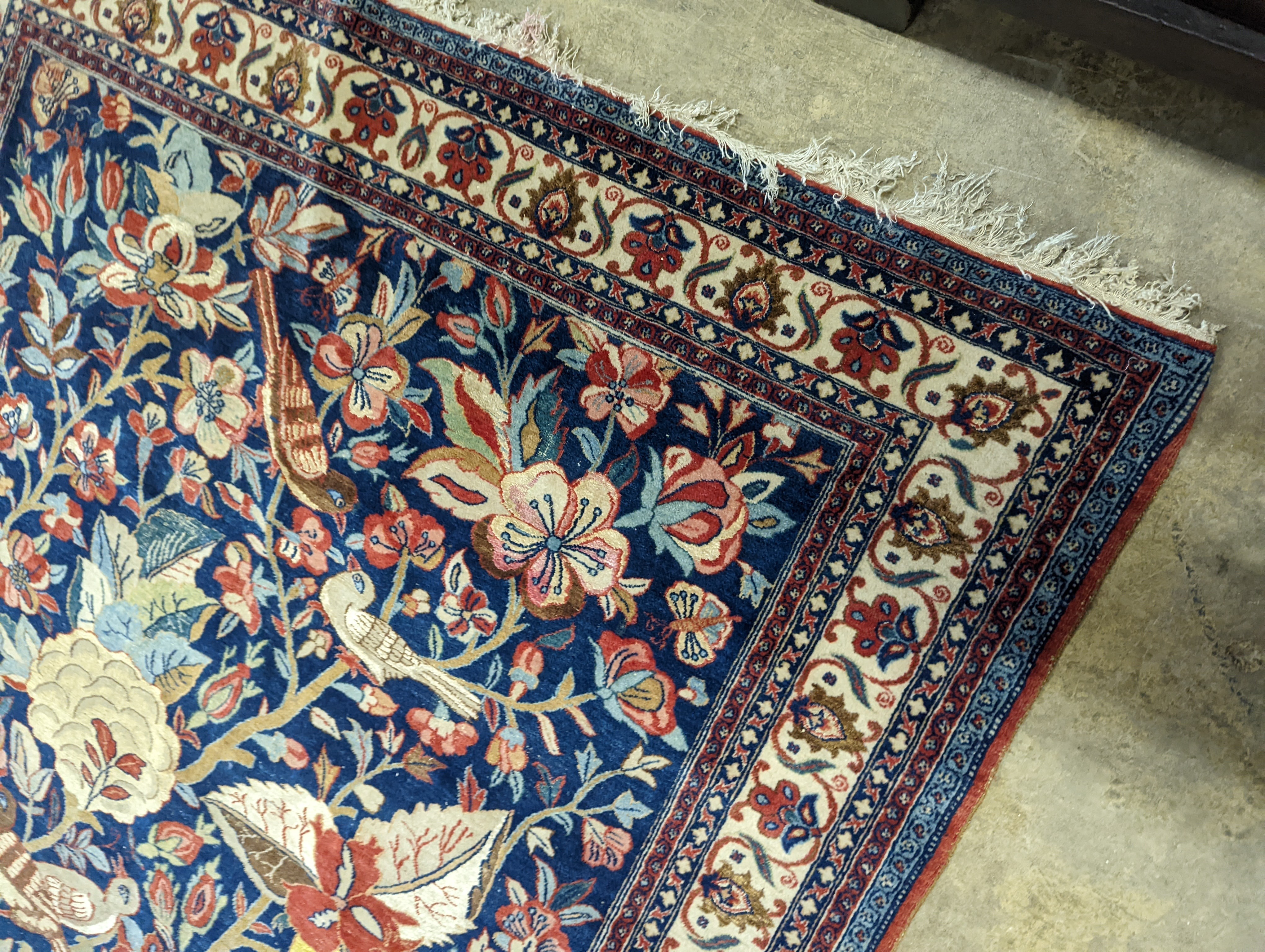 A Kirman blue ground rug woven with birds amongst flowering branches, 205 x 136cm
